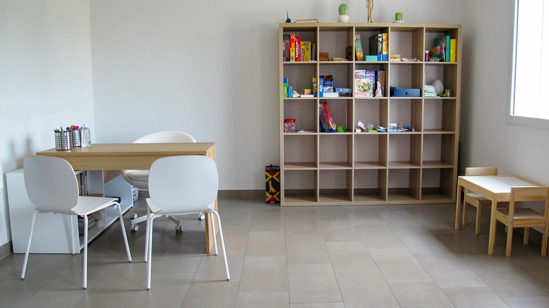 Salle du cabinet de psychomotricité, lumineuse, avec tables basses et jeux