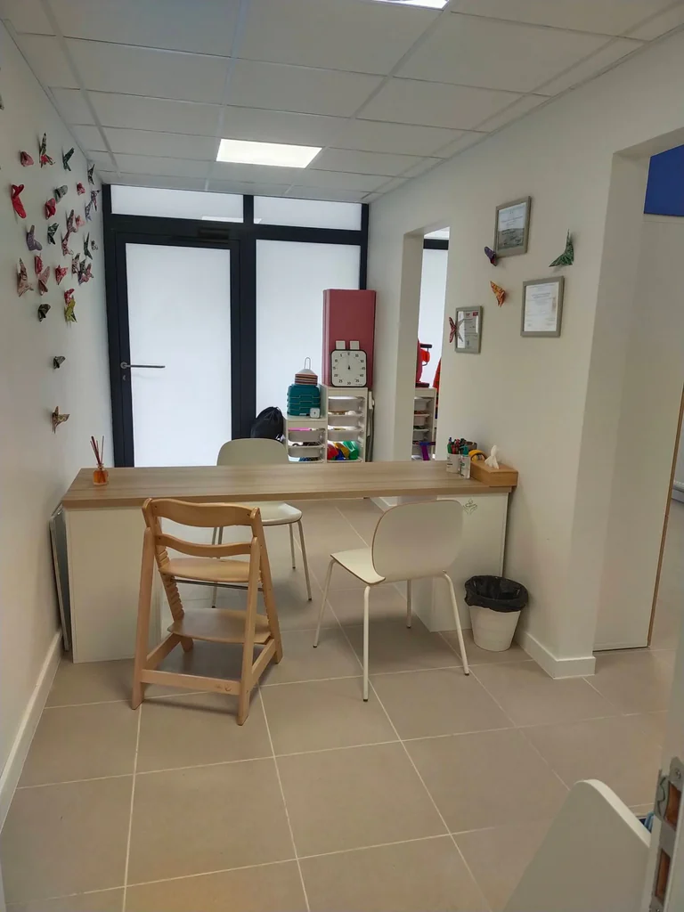Salle du cabinet de psychomotricité, 43 rue Monserby à Toulouse : table de travail, chaise évolutive et papillons en origami au mur